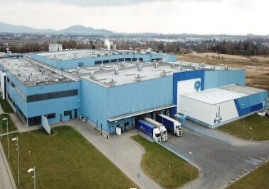 Großes blaues Logistikzentrum aus der Vogelperspektive mit LKWs an den Laderampen für Transport und Industrie-Lieferkette.